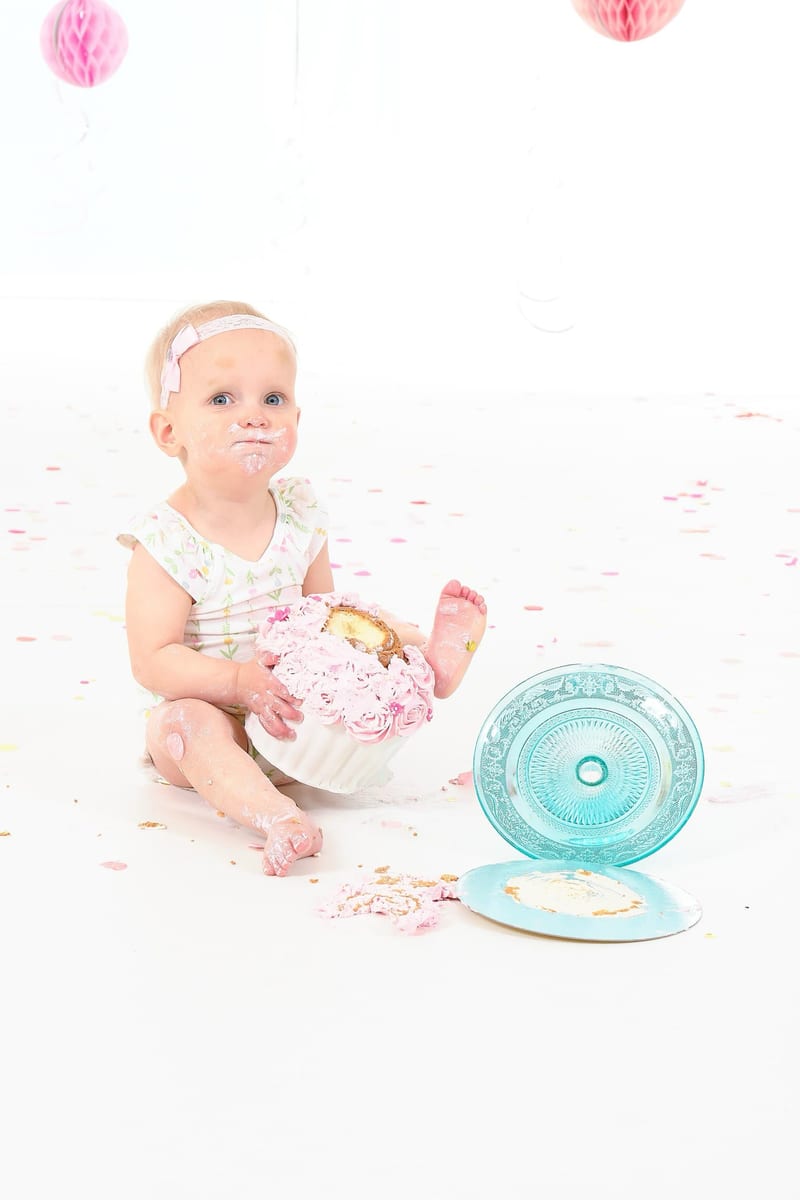 Schattig meisje eet roze taart bij cakesmash fotoshoot eerste verjaardag studio — Familieshoot Stefan Segers