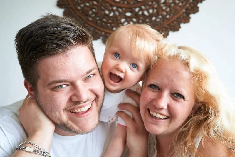 Ouders met blond peuter lachen samen in fotostudio, cakesmash eerste verjaardag Zoetermeer — Familieshoot Stefan Segers