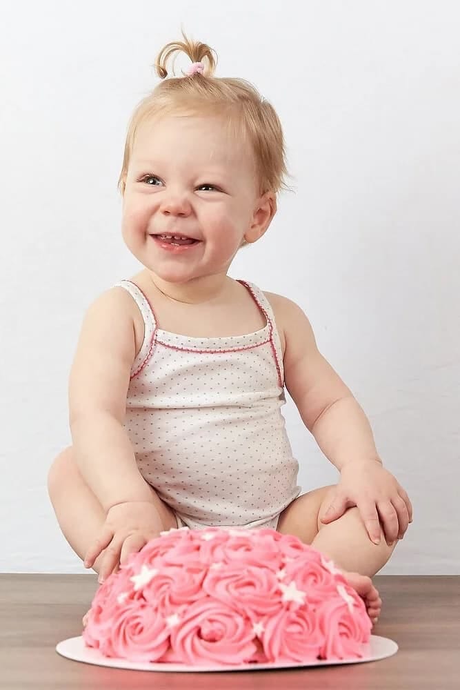 Klein meisje lacht bij roze taart, cakesmash eerste verjaardag fotoshoot studio Zoetermeer — Familieshoot Stefan Segers