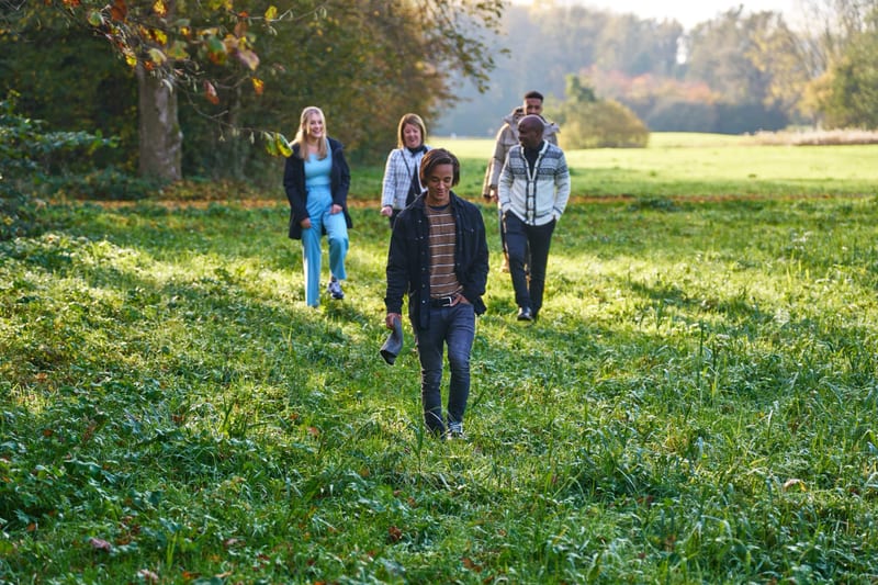 Familie wandelt samen op groen grasveld in herfstpark, gezellige familiefotoshoot Zoetermeer — Familieshoot Stefan Segers
