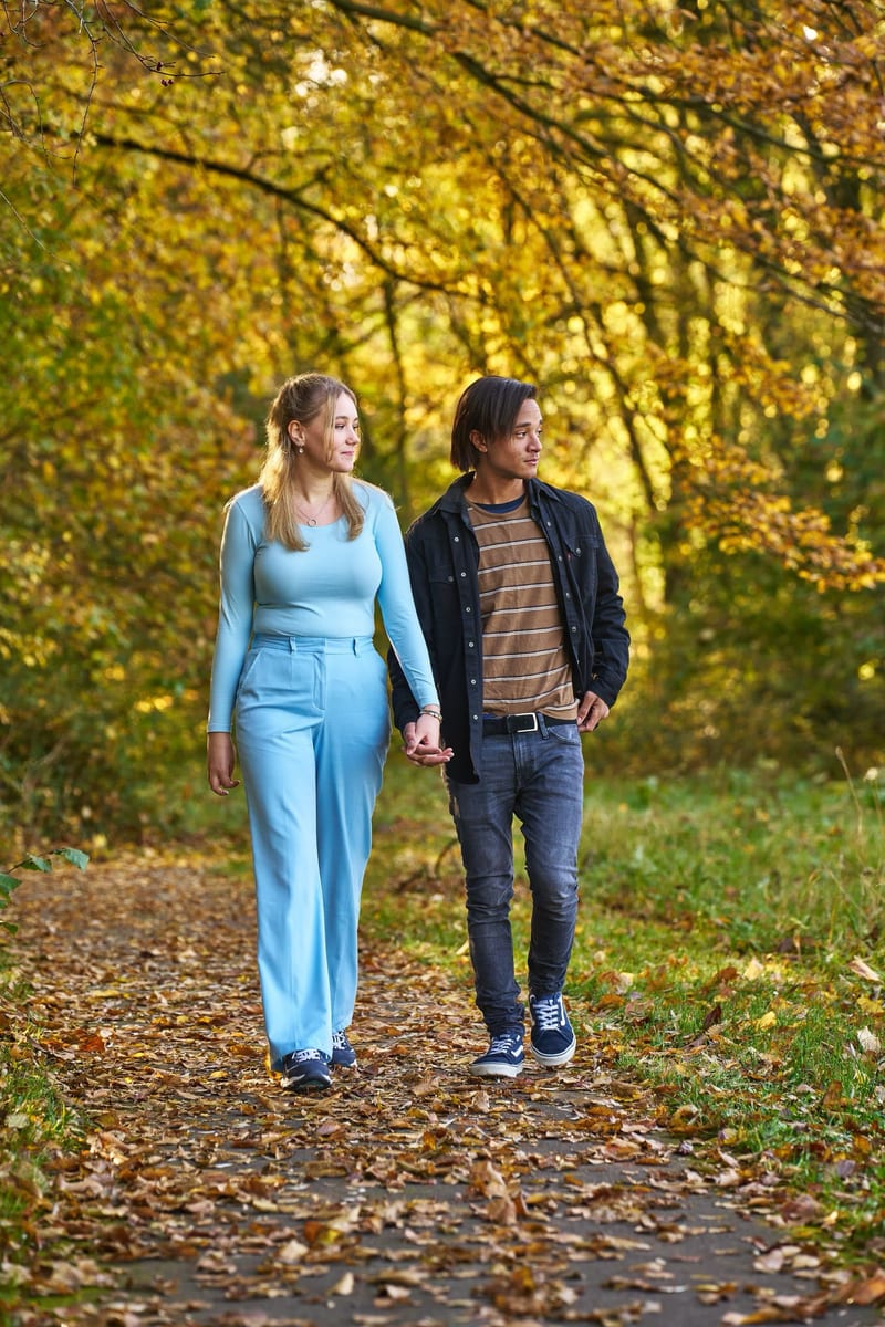 Jong stel wandelt hand in hand door herfstpark met geel bladerdak, familiefotoshoot Zoetermeer — Familieshoot Stefan Segers