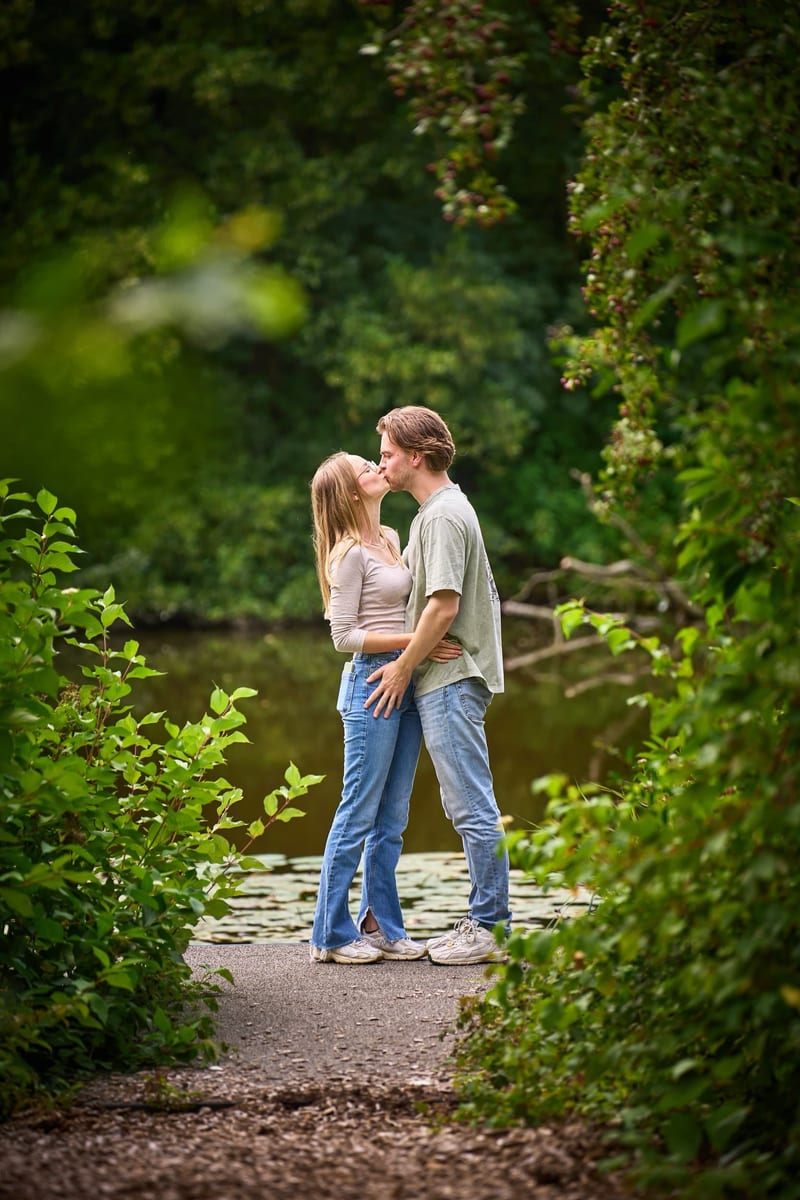 Koppel kust elkaar in groene tuingang, ontspannen familiefotoshoot Westerpark Zoetermeer — Familieshoot Stefan Segers