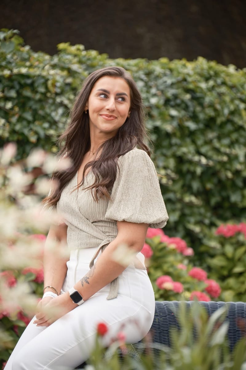 Jonge vrouw zit lachend in groene tuin met bloemen, ontspannen portret familieshoot tuin Zoetermeer — Familieshoot Stefan Seg