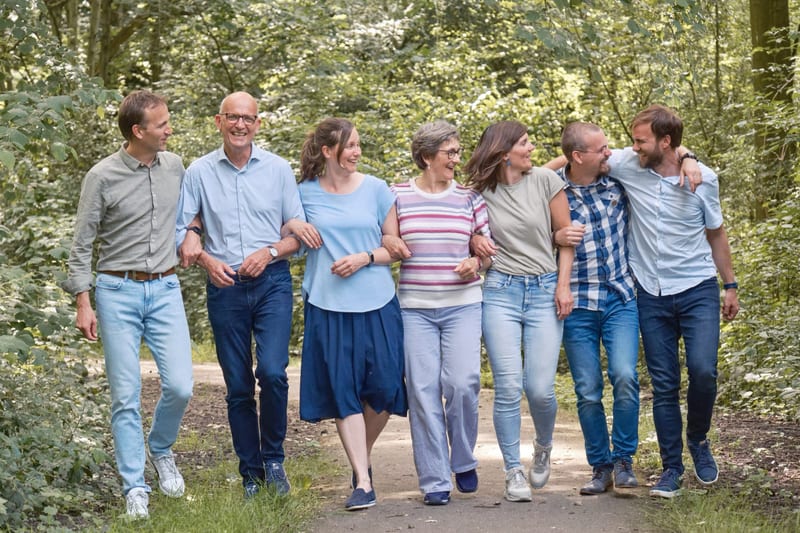 Grote familie loopt lachend samen door bospad, ontspannen familiefotoshoot Westerpark Zoetermeer — Familieshoot Stefan Segers