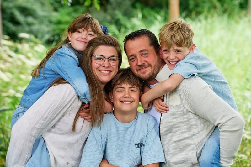 Gelukkig gezin met twee ouders en drie kinderen knuffelt elkaar in het groen, familiefotoshoot Zoetermeer — Familieshoot Stef