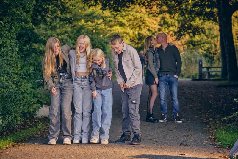 Groot gezin loopt lachend door park met herfstbomen, natuurlijke familiefotoshoot Zoetermeer — Familieshoot Stefan Segers