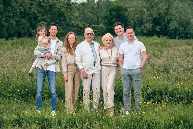 Driejarig gezin in groepsportret op wildflowerweide, multi-generatiefamilie lacht in zomerse setting — Familieshoot Stefan Se