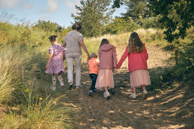 Gezin loopt hand in hand op zandpad in natuur, warme familiefotoshoot Westerpark Zoetermeer — Familieshoot Stefan Segers