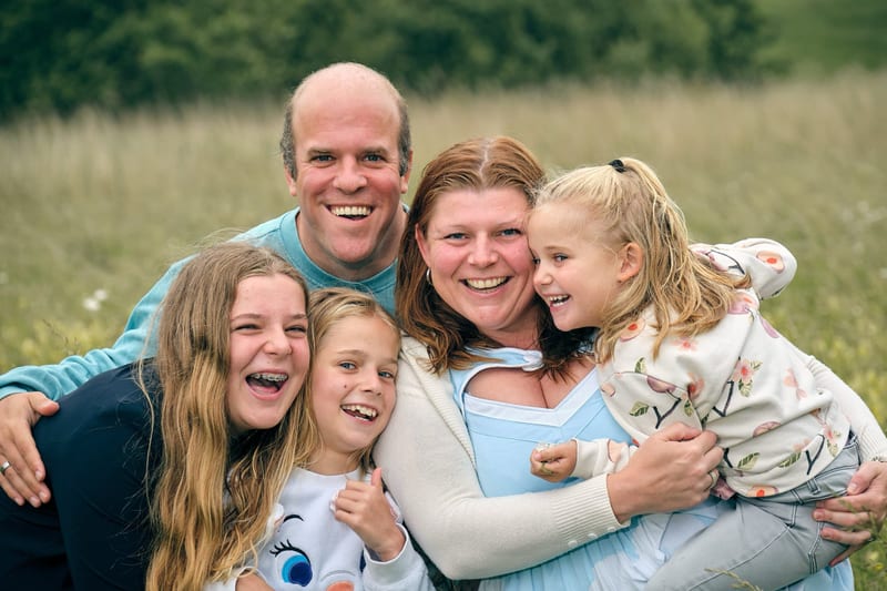 Gelukkig gezin met vier kinderen omhelst elkaar lachend in groen park, familiefotoshoot Zoetermeer — Familieshoot Stefan Sege