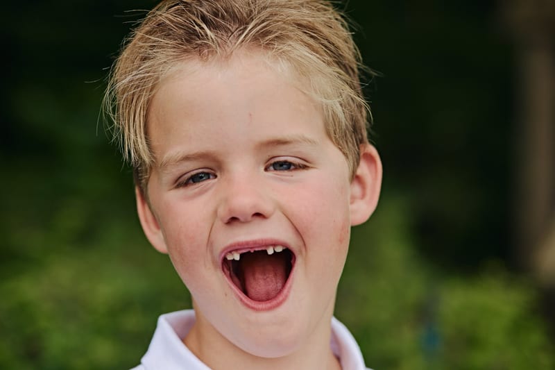 Jongentje lacht enthousiast in de tuin, speelse kinderfotoshoot familie Zoetermeer — Familieshoot Stefan Segers