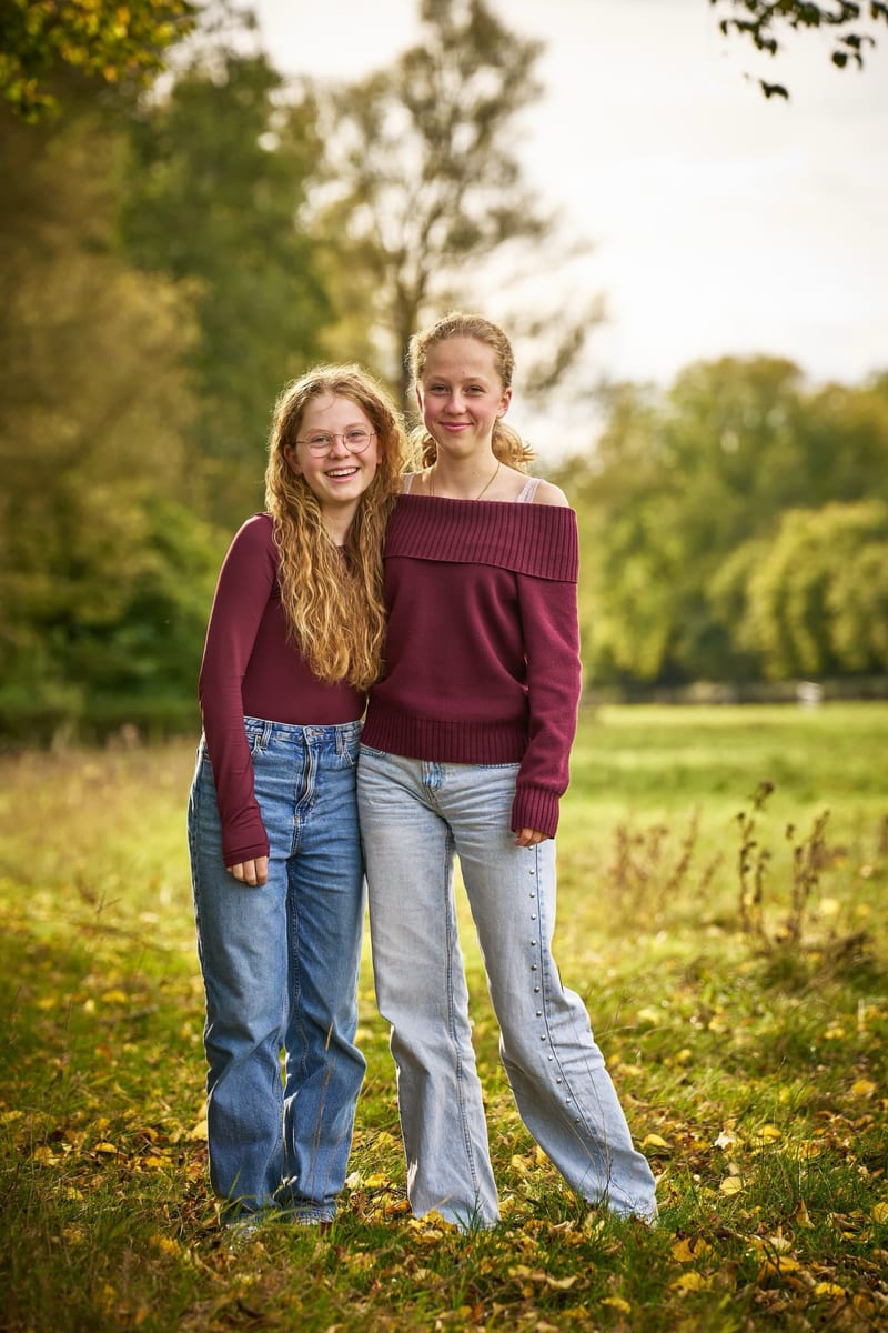 Twee meisjes lachen samen in groen park, kinderfotoshoot buiten Zoetermeer — Familieshoot Stefan Segers