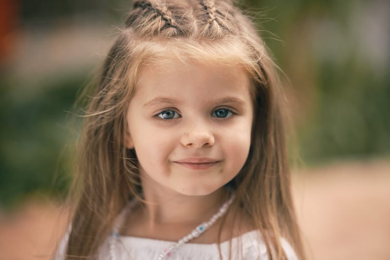 Lachend meisje met vlechten in witte jurk, professionele kinderfotografie Zoetermeer — Familieshoot Stefan Segers