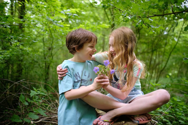 Broer en zus lachen samen in groen bos, kinderfotoshoot Zoetermeer — Familieshoot Stefan Segers