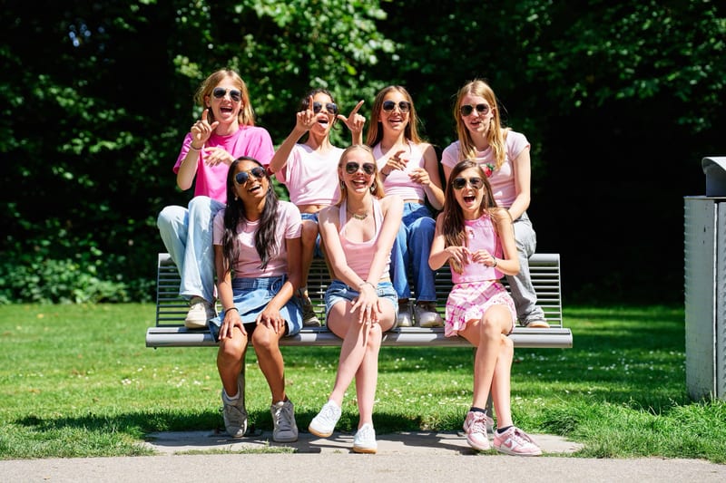 Groep meisjes zit lachend op bankje in park, kleurrijk kinderfeestje fotoshoot Zoetermeer — Familieshoot Stefan Segers