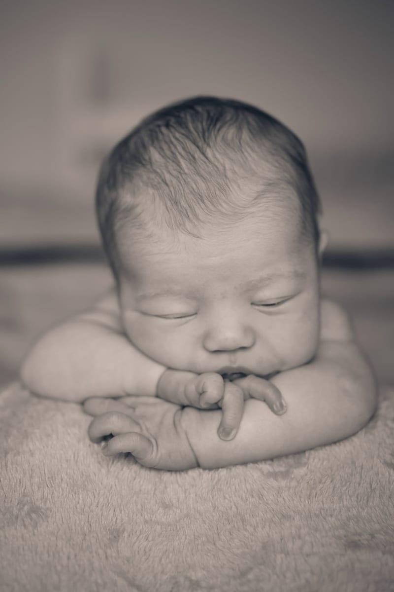 Pasgeboren baby slaapt zacht op deken, newbornfotografie zwart-wit Zoetermeer — Familieshoot Stefan Segers