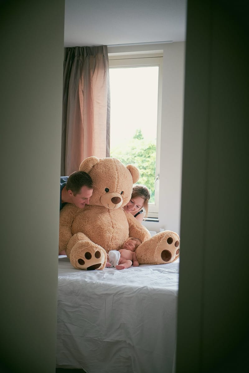 Pasgeboren baby met groot teddybeer en twee kinderen bij raam, newbornfotografie studio Zoetermeer — Familieshoot Stefan Sege