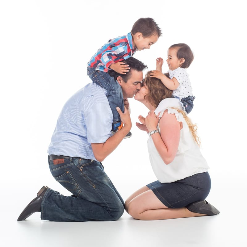 Familie met twee jongens knielt samen lachend in fotostudio, authentieke familieshoot — Familieshoot Stefan Segers