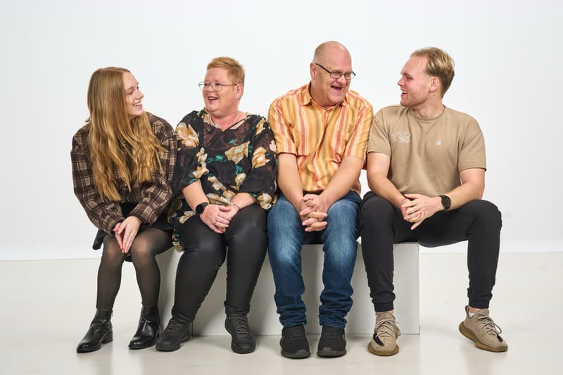 Gezin vier personen zit lachend samen op witte kubus, studiofotografie fotostudio Zoetermeer — Familieshoot Stefan Segers