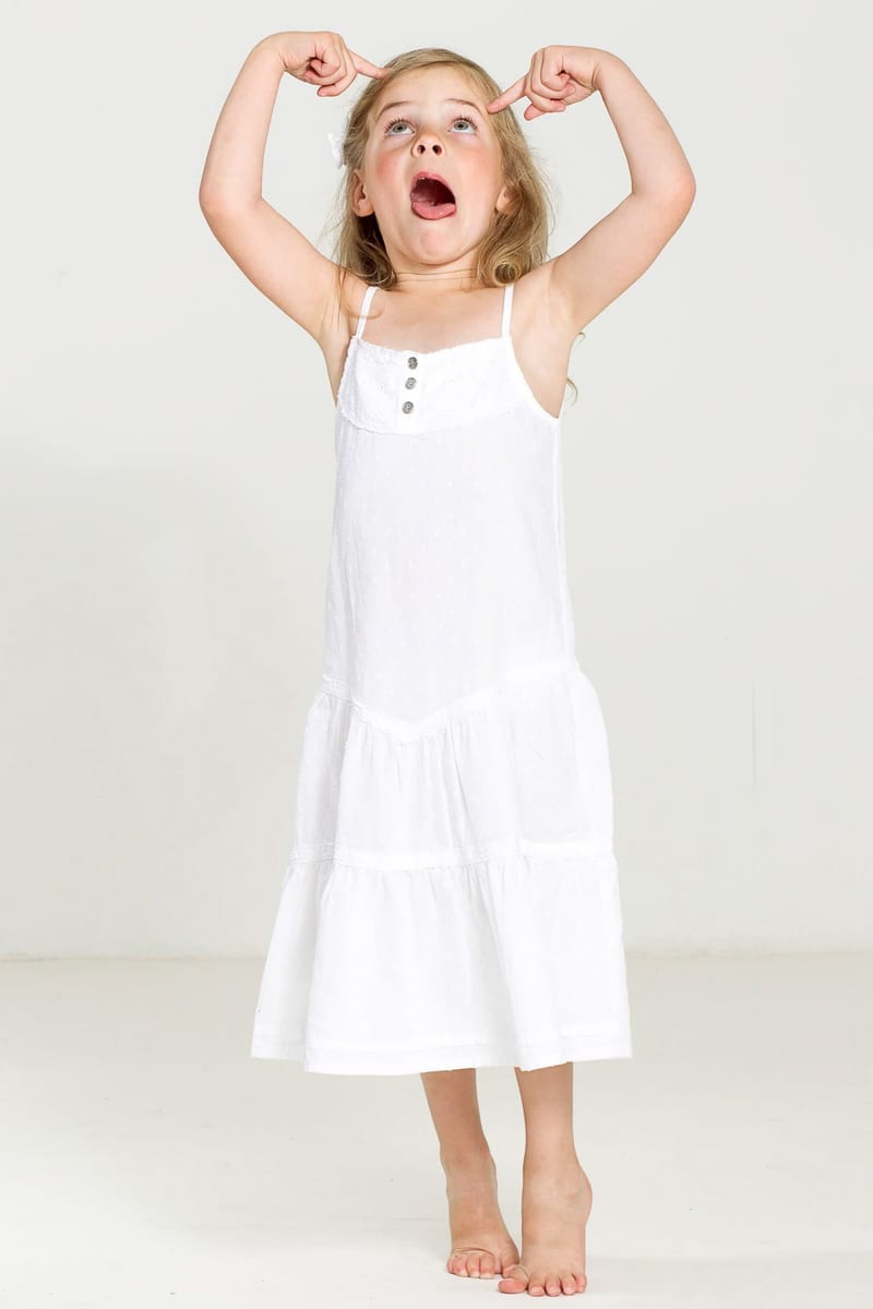 Blij meisje in witte jurk poseert speels in fotostudio, kinderportret Zoetermeer — Familieshoot Stefan Segers
