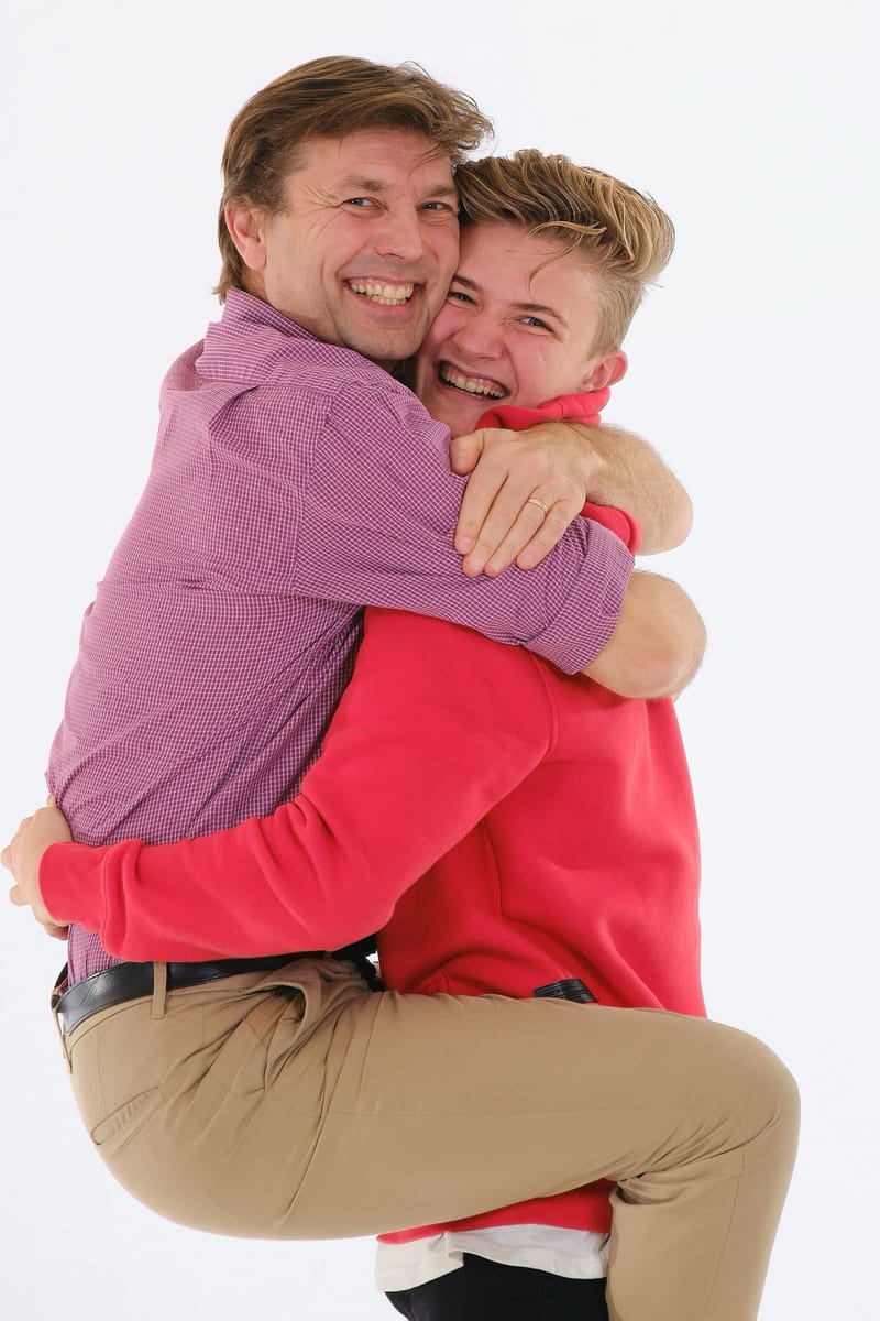 Vader tilt zoon op in fotostudio, beide lachen blij, studiofotografie familieshoot — Familieshoot Stefan Segers
