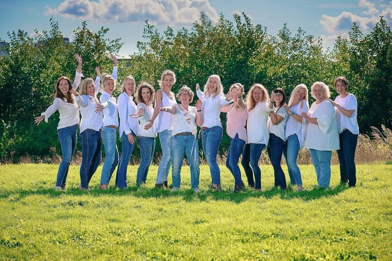 Groep vriendinnen in witte shirts en jeans poseren lachend op groen veld, vrijgezellenfeest fotoshoot Zoetermeer — Familiesho