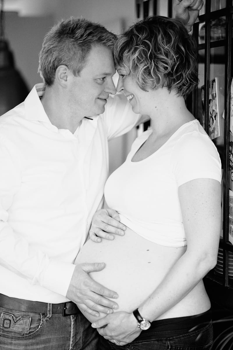 Zwanger stel knuffelt innig, man raakt buik aan in zwart-wit, maternity fotoshoot Zoetermeer — Familieshoot Stefan Segers