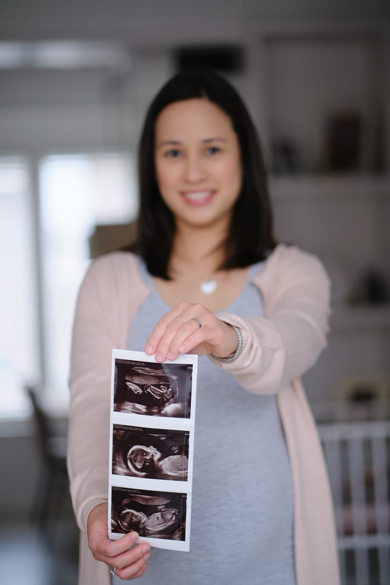Zwangere vrouw toont echofoto's met glimlach, zwangerschapsfotoshoot Zoetermeer — Familieshoot Stefan Segers