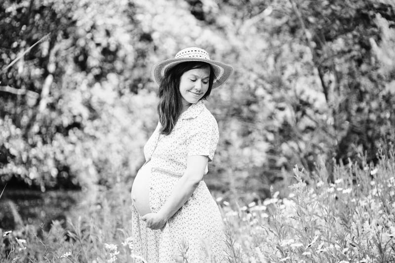 Zwangere vrouw in bloemenweide met hoed, zwangerschapsfotoshoot buiten Zoetermeer — Familieshoot Stefan Segers