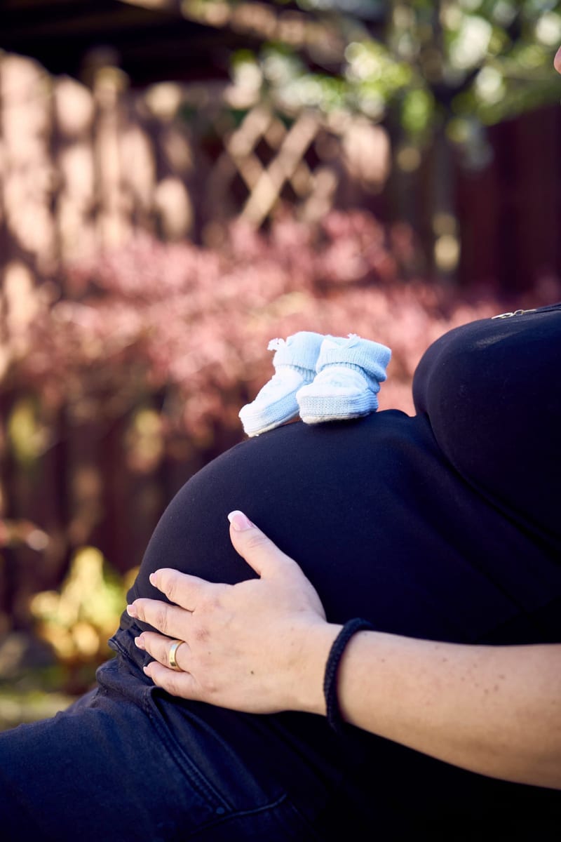 Zwangere vrouw met babyschoen op buik, intieme zwangerschapsfotografie thuis Zoetermeer — Familieshoot Stefan Segers